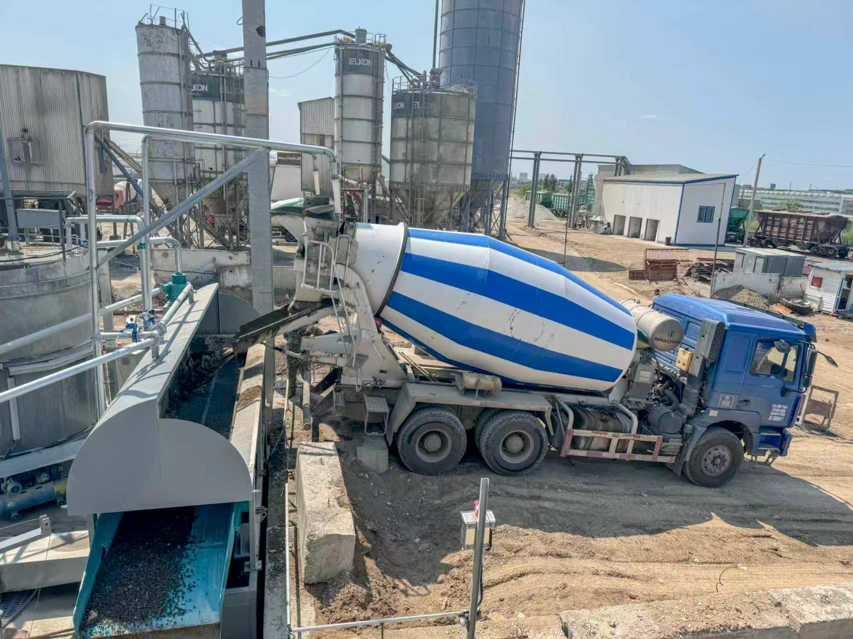 Concrete mixer truck unloading residual concrete into an Enpu concrete reclaimer at a batching plant
